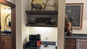A kitchen with wooden cabinets, a coffee maker, and a trash can. - Charming and Cozy Retreat in Newaygo, MI- The Rustic Barn dominium (Newaygo)