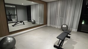 A modern, minimalist room with a large mirror, exercise equipment, and a large window with curtains. - Prime Soul Brooklin (Sao Paulo)