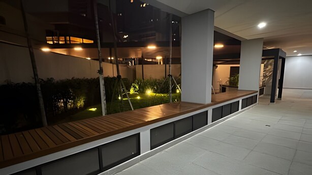 A modern indoor space with a long bench, glass walls, and a tiled floor. - Prime Soul Brooklin (Sao Paulo)