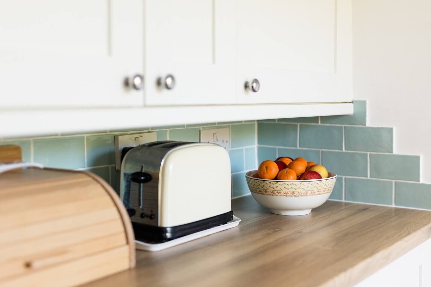 Eine Küche mit weißen Schränken, einem Toaster und einer Fruchtschale auf der Arbeitsfläche.