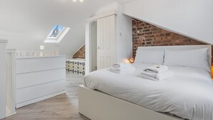 A bedroom with a white bed, a skylight, a brick wall, and a wooden floor. - Pass the Keys | Stunning 3-bed Retreat in the Heart of York (York)