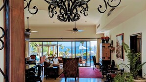 A spacious lobby with a high ceiling, ornate chandelier, and large windows offering a view of the ocean.