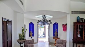 A spacious hallway with patterned armchairs, a potted plant, and a decorative ceiling light.