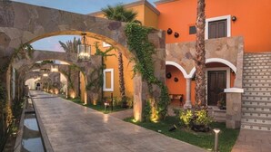A pathway leading to a building with stone arches, a palm tree, and outdoor lighting. - Luxury 3-bedroom Villa in Hacienda Encantada, Los Cabos. (B.C.S.)