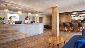 A reception area with a bar, seating, and a reception desk. - Kyriad Sens (Sens)