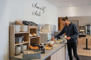 A breakfast bar with a coffee machine, bowls, and plates.