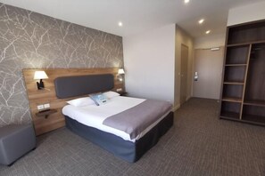 A hotel room with a bed, bedside tables, a wardrobe, and a wall with a tree branch pattern. - Kyriad Sens (Sens)