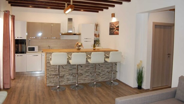 Une cuisine moderne avec un îlot central, des tabourets de bar et un plafond en bois.
