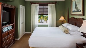 Een hotelkamer met een bed, een televisie, een raam met gordijnen, een lamp en een schilderij aan de muur.