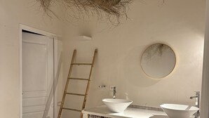 A bathroom with a bathtub, two sinks, a mirror, and a ladder.