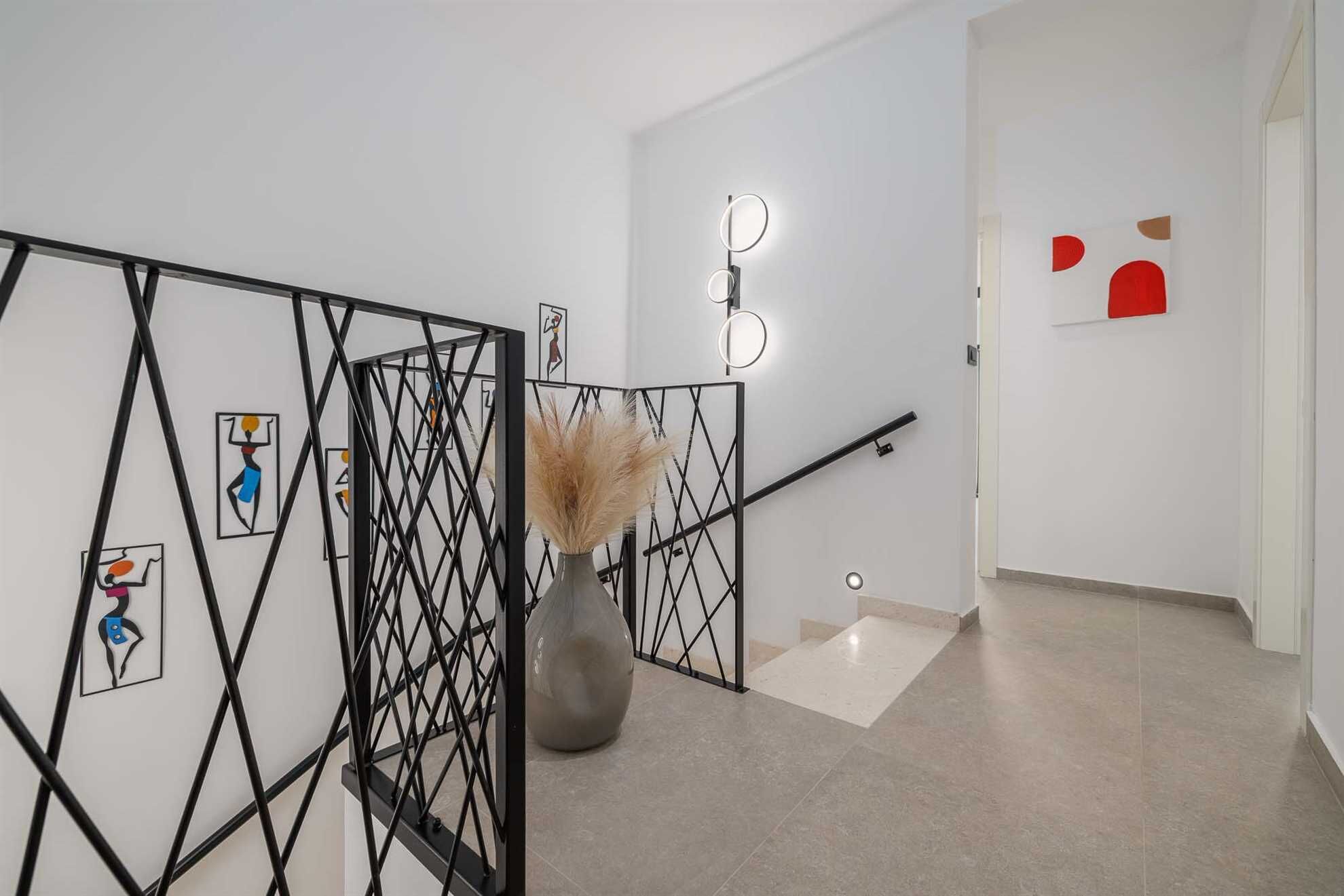 Un intérieur moderne agrémenté d’une cloison en métal noir aux motifs géométriques, d’un vase contenant des herbes des pampas séchées et d’œuvres d’art murales abstraites.