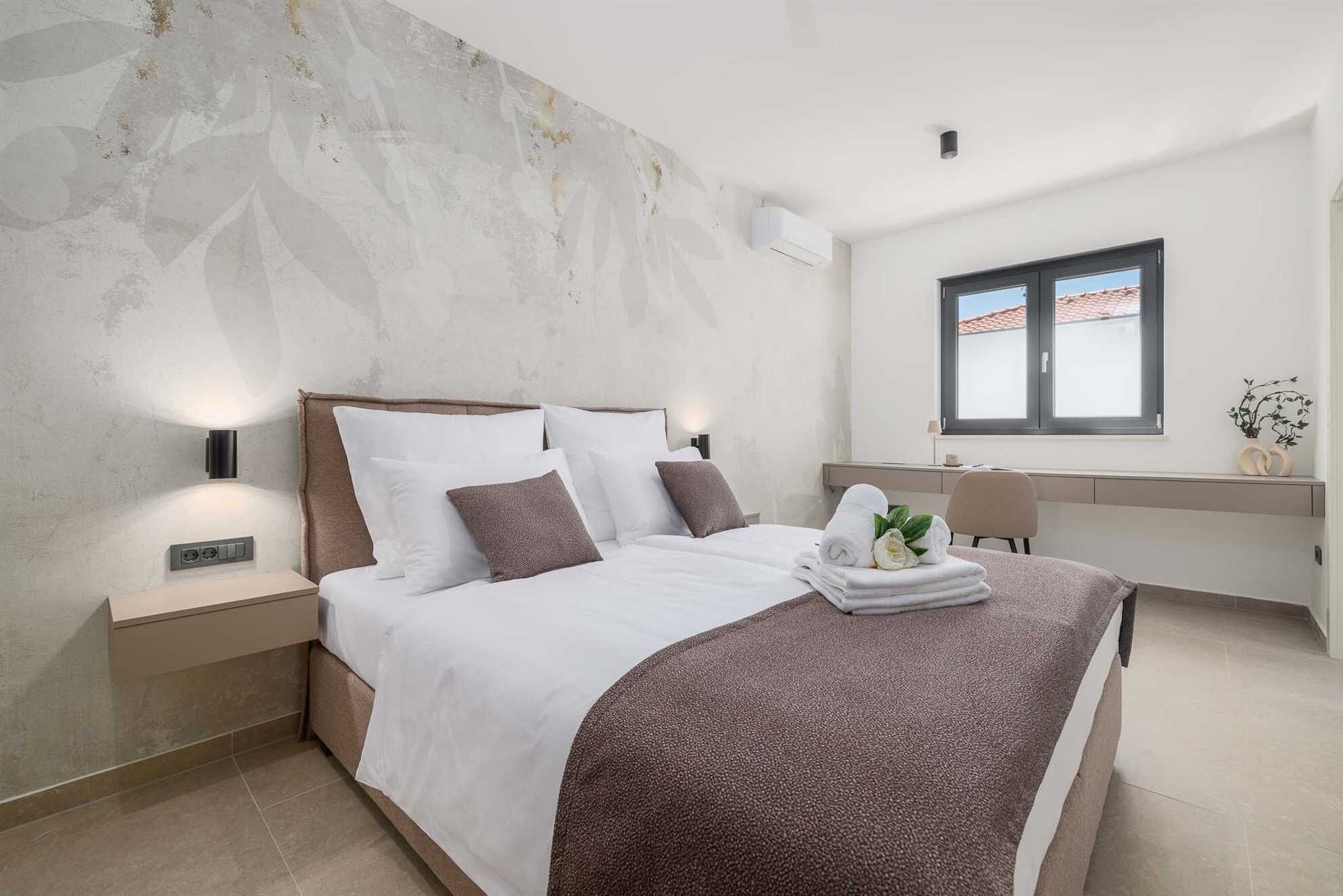 A modern bedroom with a bed, nightstands, a desk, and a window.