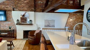 A modern kitchen with a large island, a fireplace, and a dining area with leather seating. - 4 King Suites, Downtown, Outlets, Beach, Historic (Portsmouth)