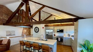 A spacious kitchen with a central island, wooden beams, and a brick wall. - 4 King Suites, Downtown, Outlets, Beach, Historic (Portsmouth)