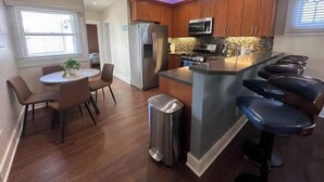 A modern kitchen with wooden cabinets, stainless steel appliances, and a bar area with stools. - Sunny condo by the Bay! [unit B] (San Diego)