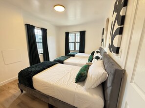 A hotel room with two beds, a large window with curtains, a ceiling light, and a wall with a large abstract painting. - Modern 2Br + Sofa Bed + 2Bth in Miracle Mile (Los Angeles)