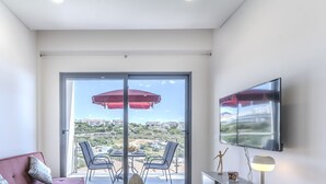 Un balcon avec une table, des chaises et un parasol rouge.
