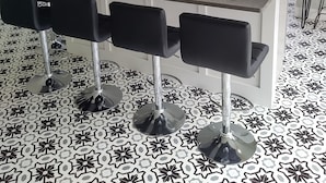 Cocina moderna con una isla central, taburetes de bar y baldosas de suelo estampadas.