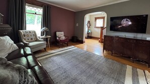 A living room with a sofa, armchair, TV, and wooden cabinet. - The Bly House (Fulton)