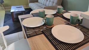 A dining area with a table set for four, including plates, cups, and cutlery. - Cozy apartment in heart of Santa Tecla (Santa Tecla)