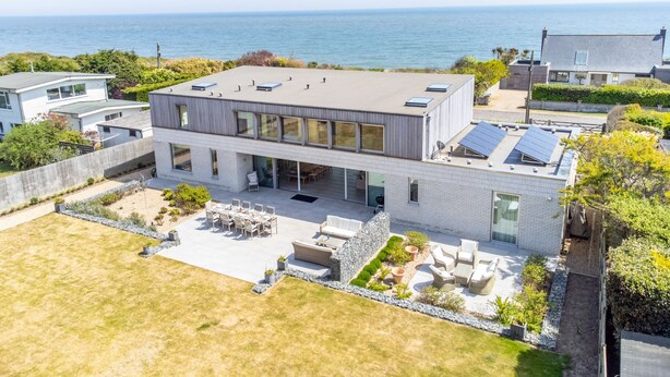 A modern two-story house with a large patio area, a swimming pool, and a view of the ocean. - Heath House, Thorpeness (Thorpeness)