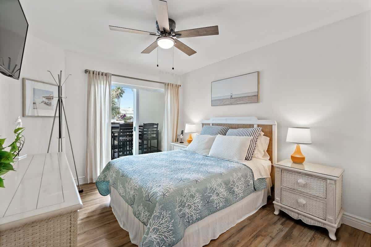 Une chambre à coucher avec un lit, des lampes de chevet, un ventilateur de plafond et une vue sur l’extérieur.