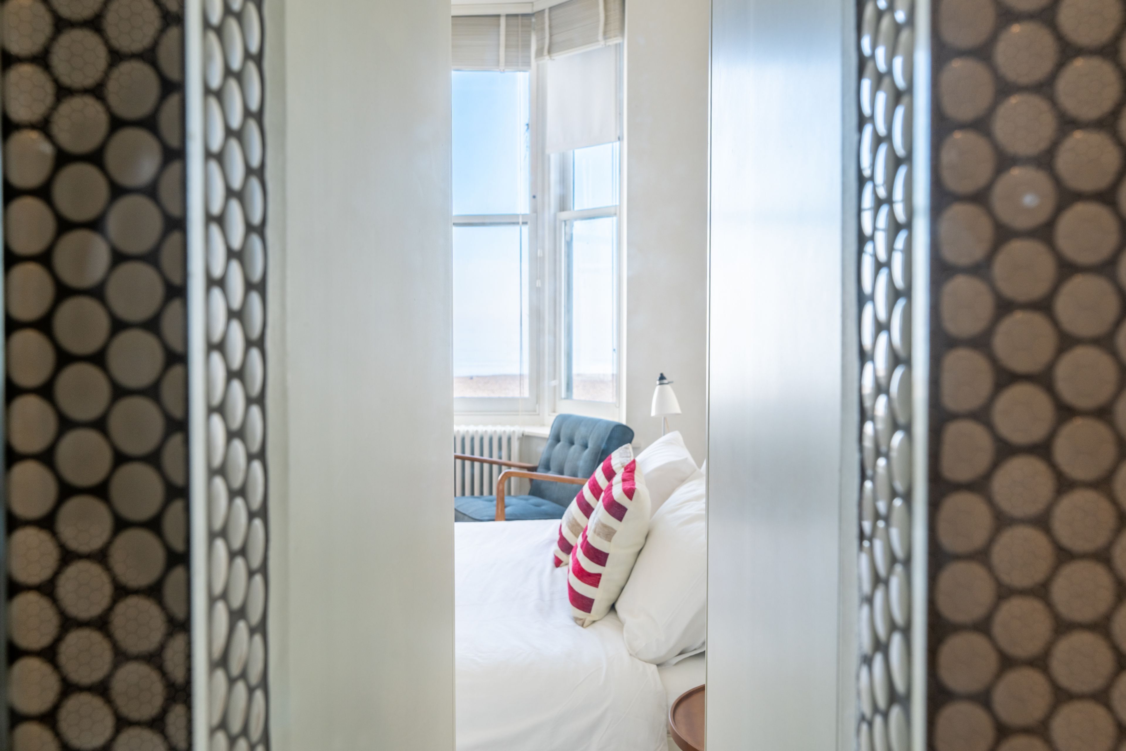 A bedroom with a bed, pillows, a chair, and a window.