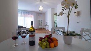 A dining table with a bottle of wine, two glasses, and a bowl of fruit. - The Regin - by Be Your Home (Civitavecchia)