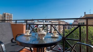 A round table with a glass top and a chair, set on a balcony with a view of buildings and trees. - The Regin - by Be Your Home (Civitavecchia)