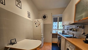 A compact kitchen with a dining area, a washing machine, and a window with blinds. - Giulio's Apartment - by Be Your Home (Rome)