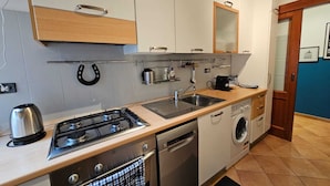 A compact kitchen with a gas stove, dishwasher, and a built-in oven. - Giulio's Apartment - by Be Your Home (Rome)