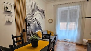 A dining area with a black table and chairs, a yellow table runner, and a potted plant. - Giulio's Apartment - by Be Your Home (Rome)