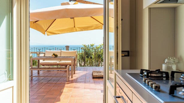 A view of a balcony with a table and chairs, a yellow umbrella, and a view of the sea. - Terrazza Aphrodite - Two Bedroom Apartment, Sleeps 5 (Salerno)