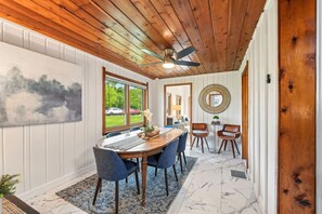 Un espace repas doté d’un plafond en bois, d’une grande fenêtre et d’une vue sur l’extérieur.