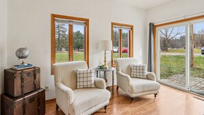 Una habitación con dos sillones, una mesita con lámpara y un globo sobre una maleta.