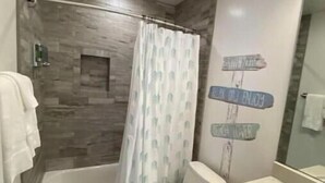 A modern bathroom with a shower, toilet, and sink.