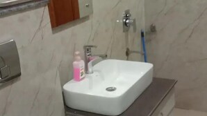 A bathroom with a toilet, sink, and mirror. - BJ Villa (Mohali)