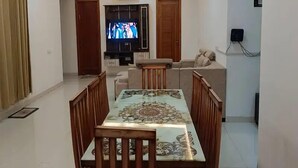 A living room with a TV, sofa, and dining table. - BJ Villa (Mohali)