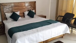 A neatly made bed with a wooden headboard, white and teal bedding, and two bedside tables with lamps. - BJ Villa (Mohali)