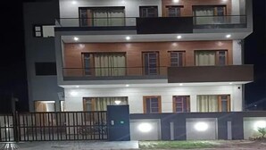 A modern multi-story residential building with a gated entrance, multiple balconies, and evenly spaced windows. - BJ Villa (Mohali)