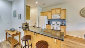 A kitchen with wooden cabinets, a granite countertop, a refrigerator, and a microwave. - Game & Movie Rooms! Unit 4 Mi to Branson Landing (Branson)