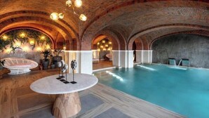 An indoor swimming pool with a brick ceiling, a round table with a vase, and lounge chairs. - 2-bedroom resort in fabulous B.C.S. with WiFi, AC, fitness room (B.C.S.)