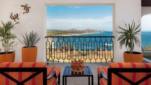 A balcony with striped cushions, a small table, and potted plants. - 2-bedroom resort in fabulous B.C.S. with WiFi, AC, fitness room (B.C.S.)