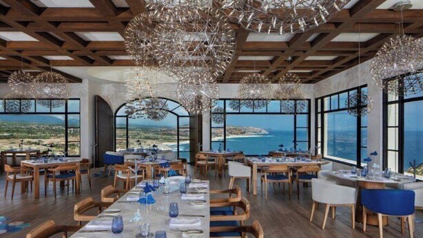 A restaurant with a long table set for dining, large windows with a view of the sea, and hanging crystal chandeliers. - 2-bedroom resort in fabulous B.C.S. with WiFi, AC, fitness room (B.C.S.)