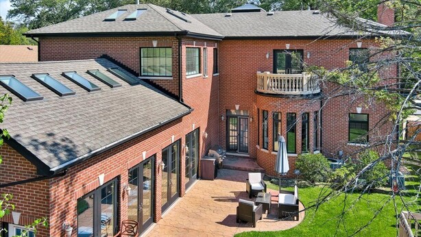 Ein zweigeschossiges Backsteinhhaus mit Terrasse, großen Fenstern und einem Balkon.