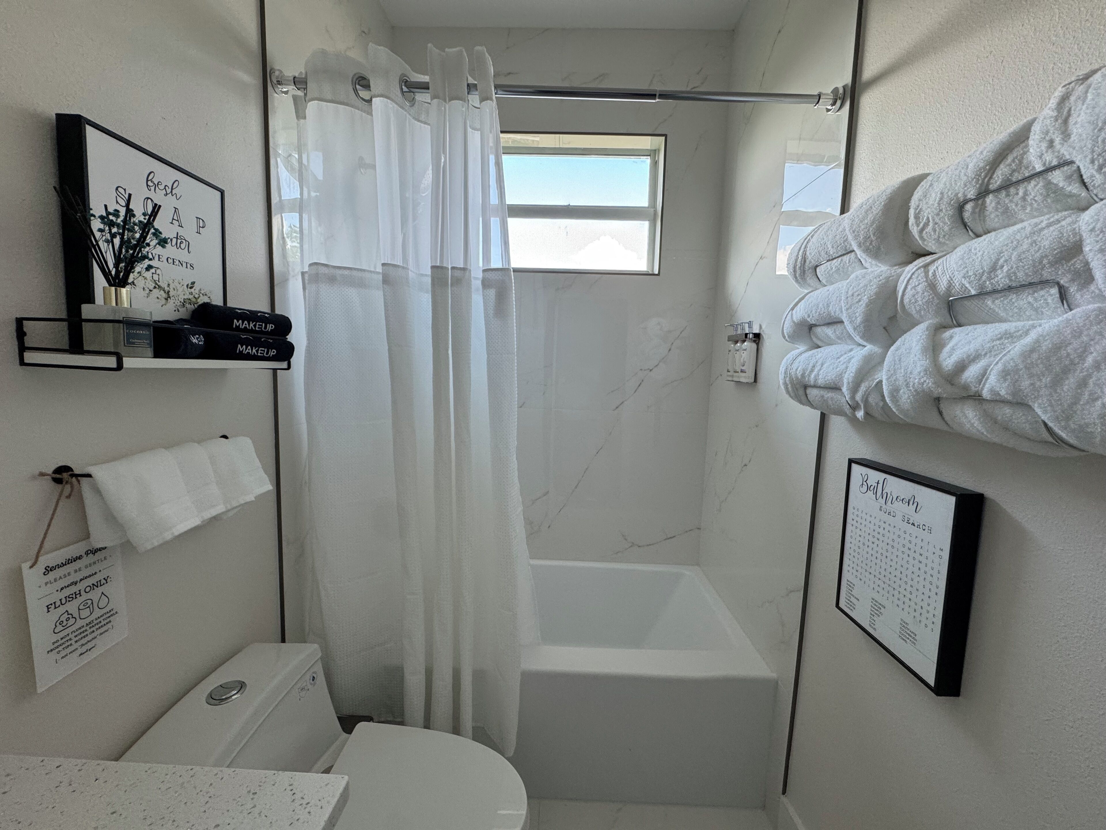 A bathroom with a shower, a toilet, a sink, and a towel rack.