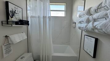 A bathroom with a shower, a toilet, a sink, and a towel rack.