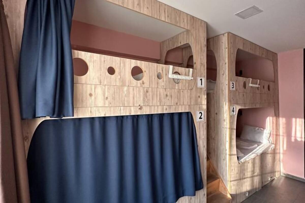 A room with bunk beds labeled 1, 2, 3, and 4, wooden walls, and a curtain.