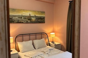 A hotel room with a bed, two bedside tables, a lamp, and a painting on the wall. - Archeo Cafe and Hostel (Istanbul)