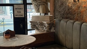 A corner of a room with a leather couch, a statue, and a sign reading "Entrance Push Welcome." - Archeo Cafe and Hostel (Istanbul)